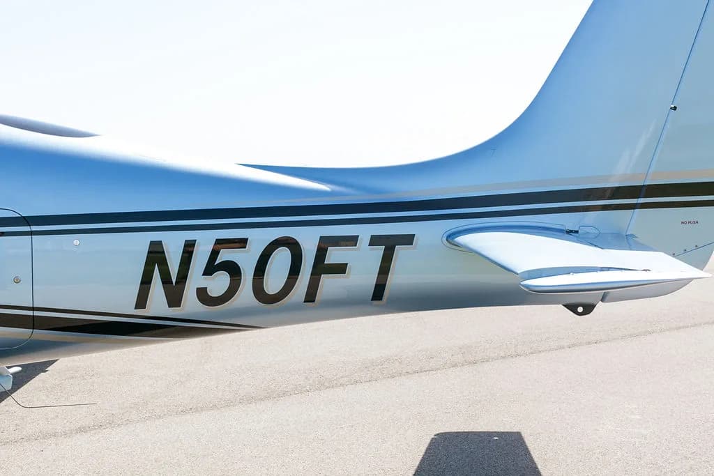 A close-up view of the light blue Cirrus SR22 aircraft's tail section with the registration N50FT.