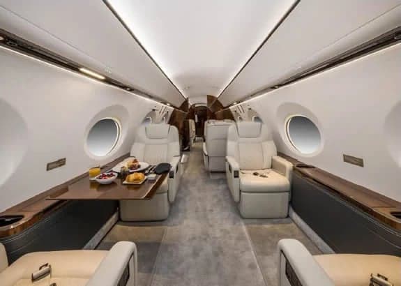 Aircraft interior with cream-colored leather seats and a table set with food.