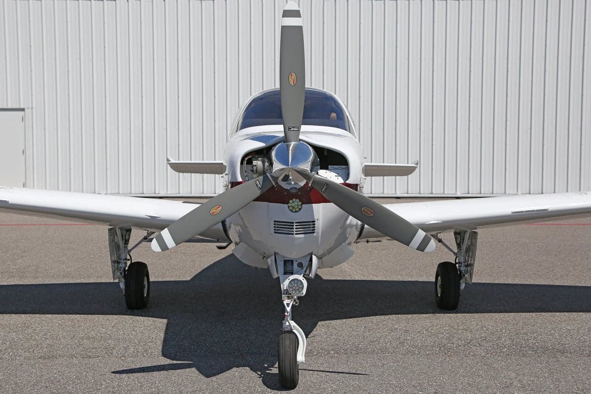 Front view of a white and red Beechcraft Bonanza aircraft with its propeller visible.