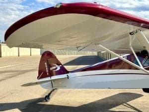 Close up of the tail of a red and white Carbon Cub aircraft on the ground.