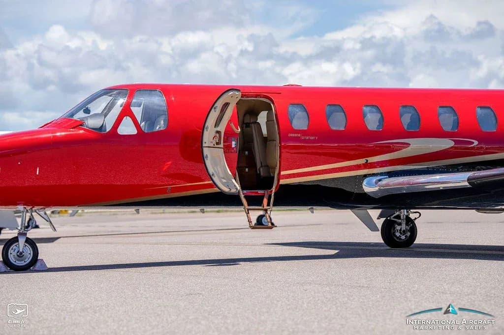 A close-up side view of the red and black Cessna Citation V (N300CH) jet with its main cabin door open.