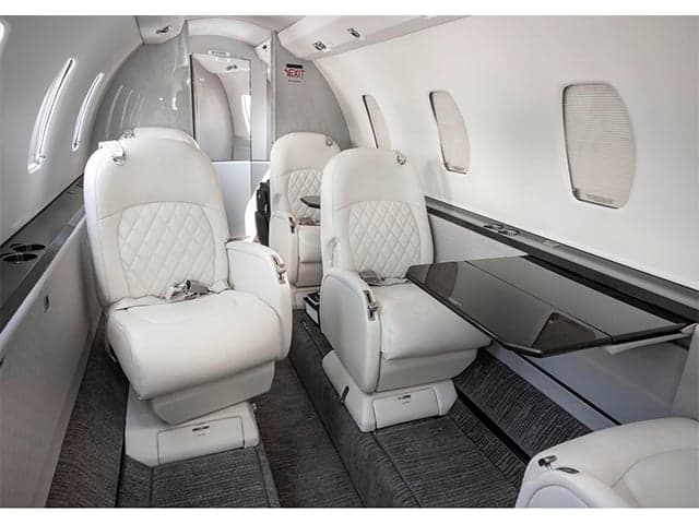 The interior of the aircraft features white leather seats and a table.