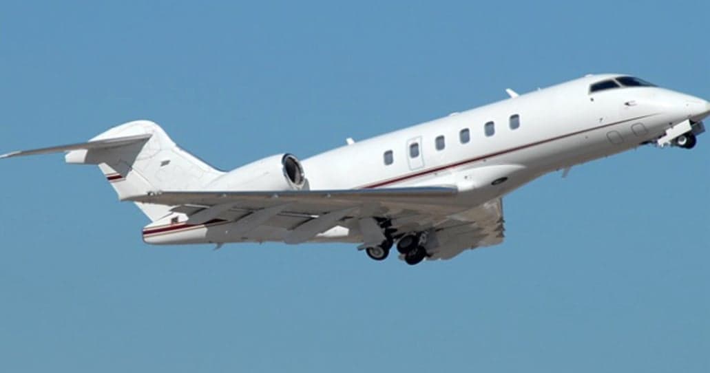 White jet aircraft taking off against a blue sky.