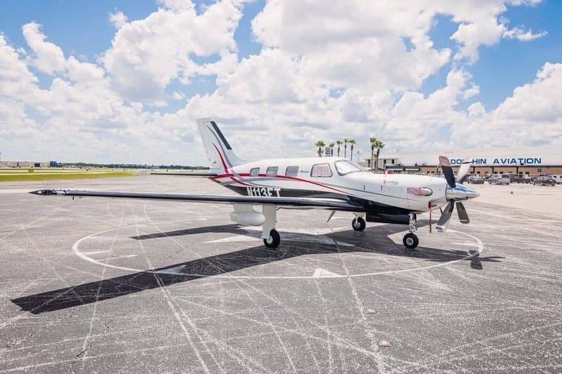 Piper Meridian aircraft parked on the tarmac with a building in the background.