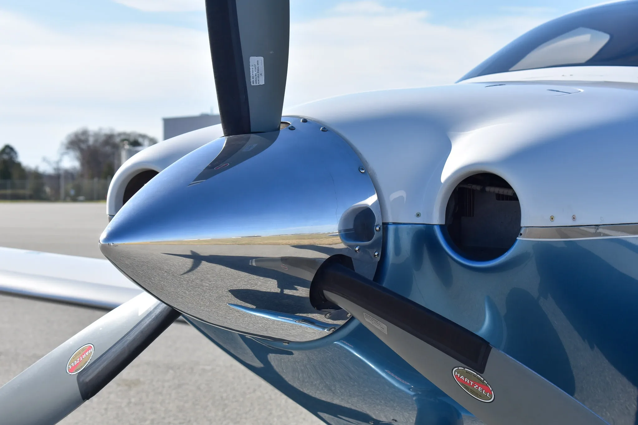 A close-up view of the polished propeller spinner and nose of the white and blue aircraft.