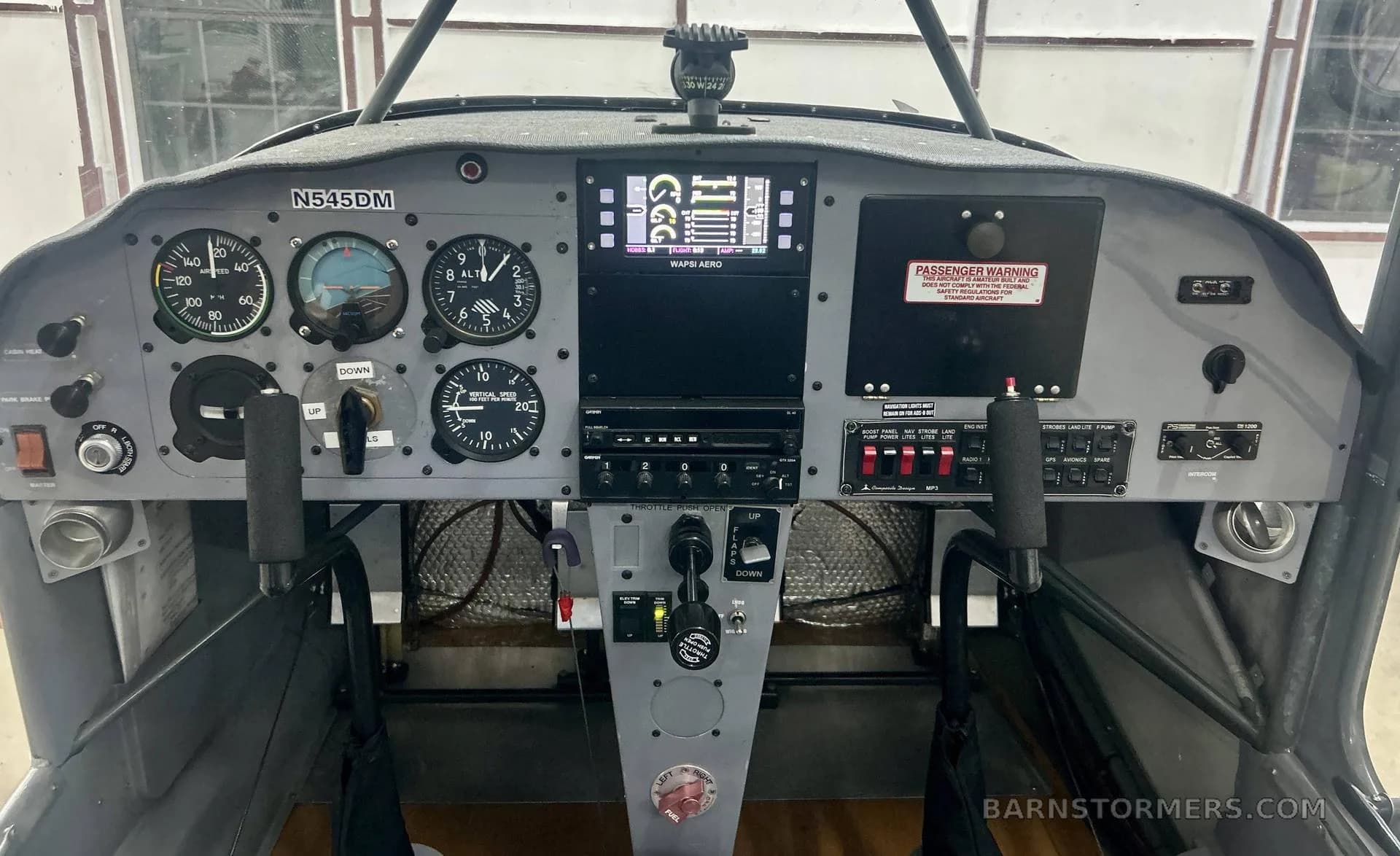 The cockpit of an aircraft shows a mix of analog gauges and a modern digital display.
