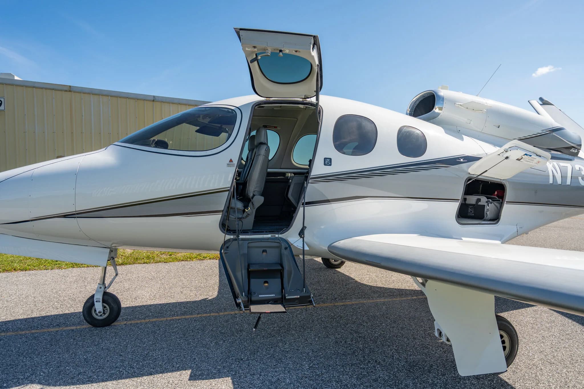 Close-up view of the open main door and front cargo compartment of the Cirrus Vision Jet N73SG.