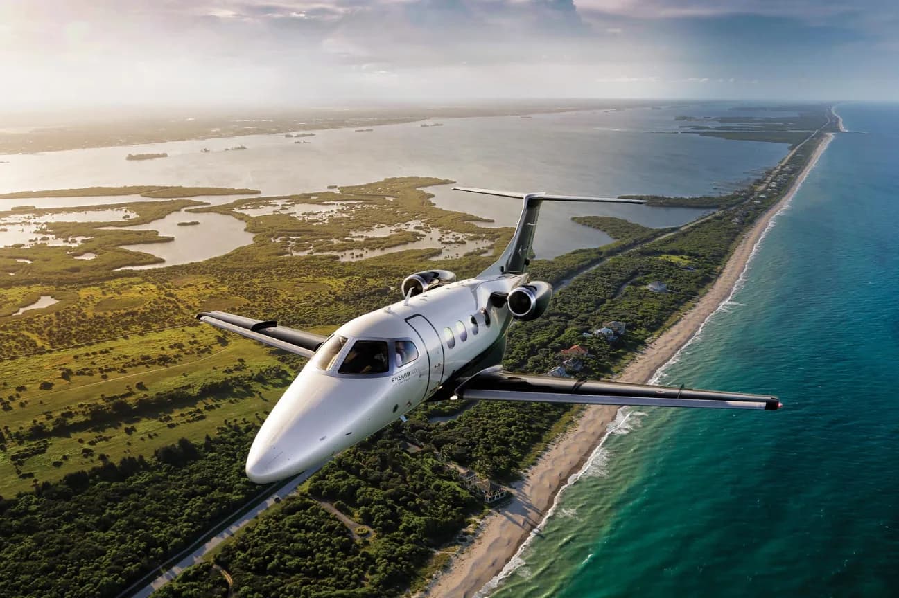 A light-colored jet flying over a coastline.