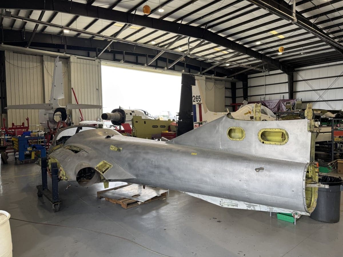 The rear section of an aircraft undergoing restoration in a hangar.