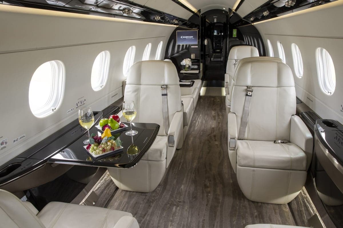 Interior view of the Embraer Legacy 500 cabin with white leather seats.