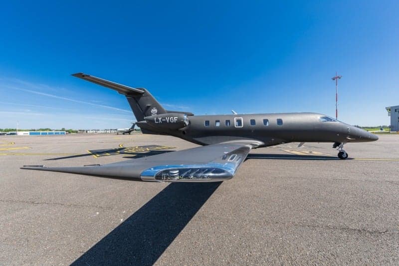 A Bombardier Challenger 350 aircraft with registration LX-VGF is parked on the tarmac at an airport.