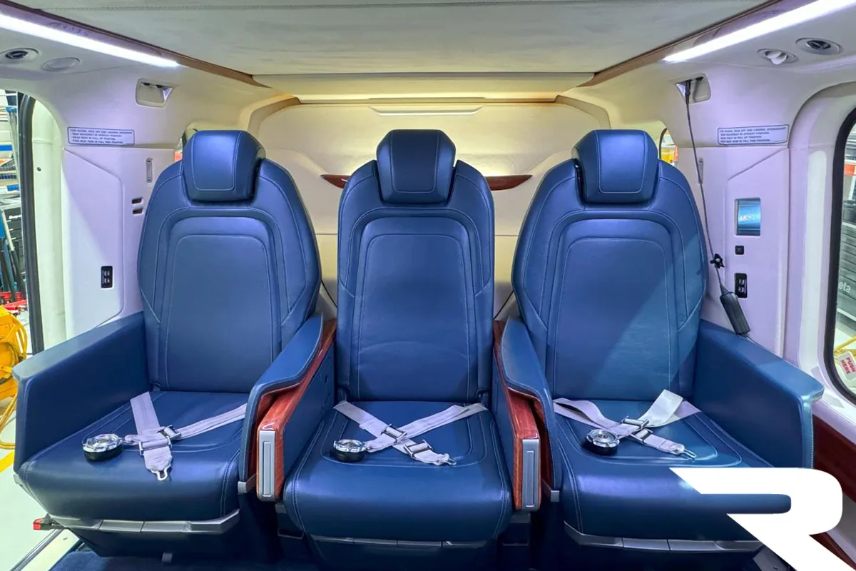 Front-facing view of three blue leather passenger seats in a helicopter cabin.