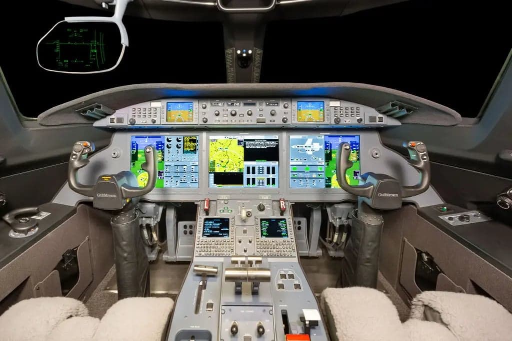 The cockpit of a Gulfstream jet features multiple display screens and controls.