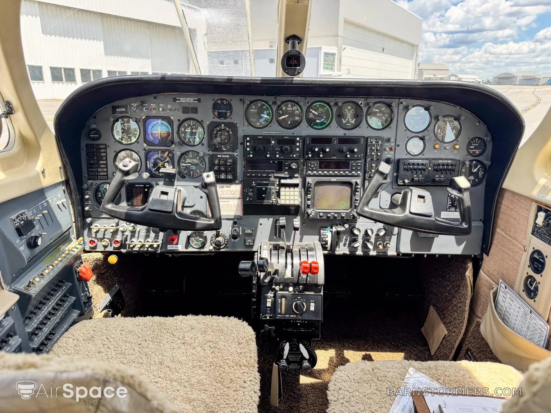 The cockpit instrument panel of a twin-engine aircraft, featuring analog gauges and two control yokes.
