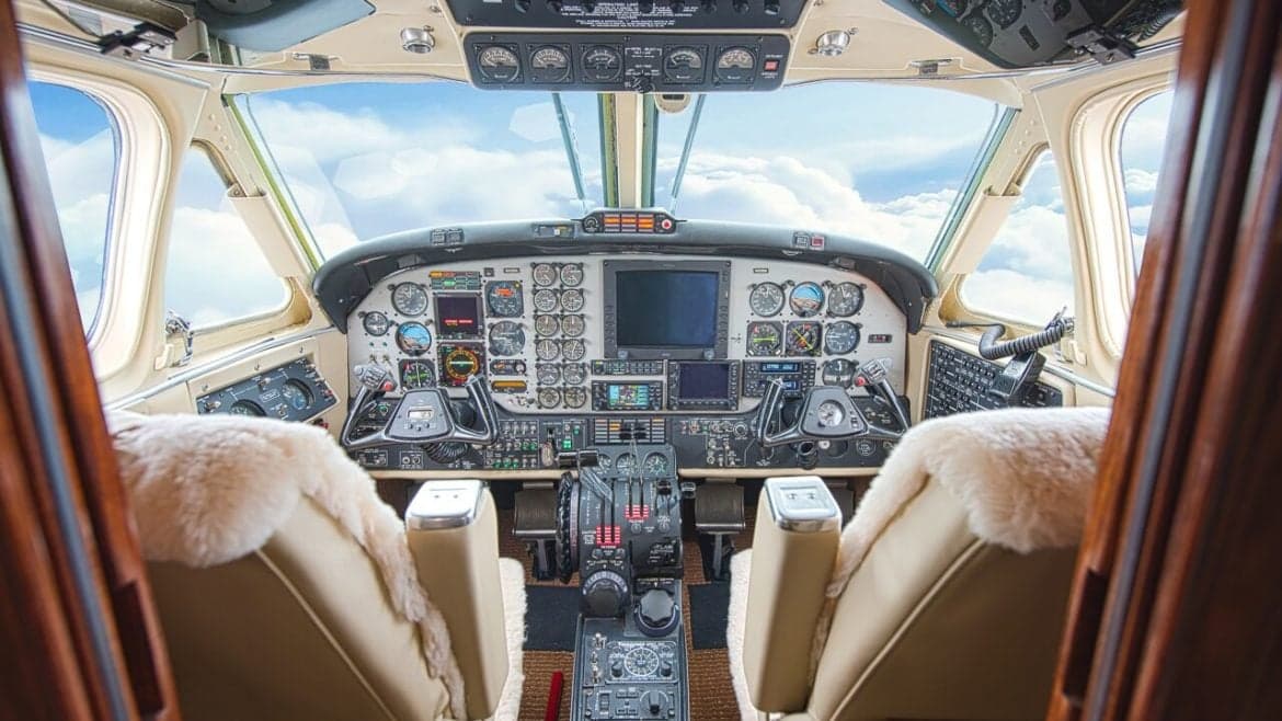 Aircraft cockpit with instrument panel and sheepskin seat covers.