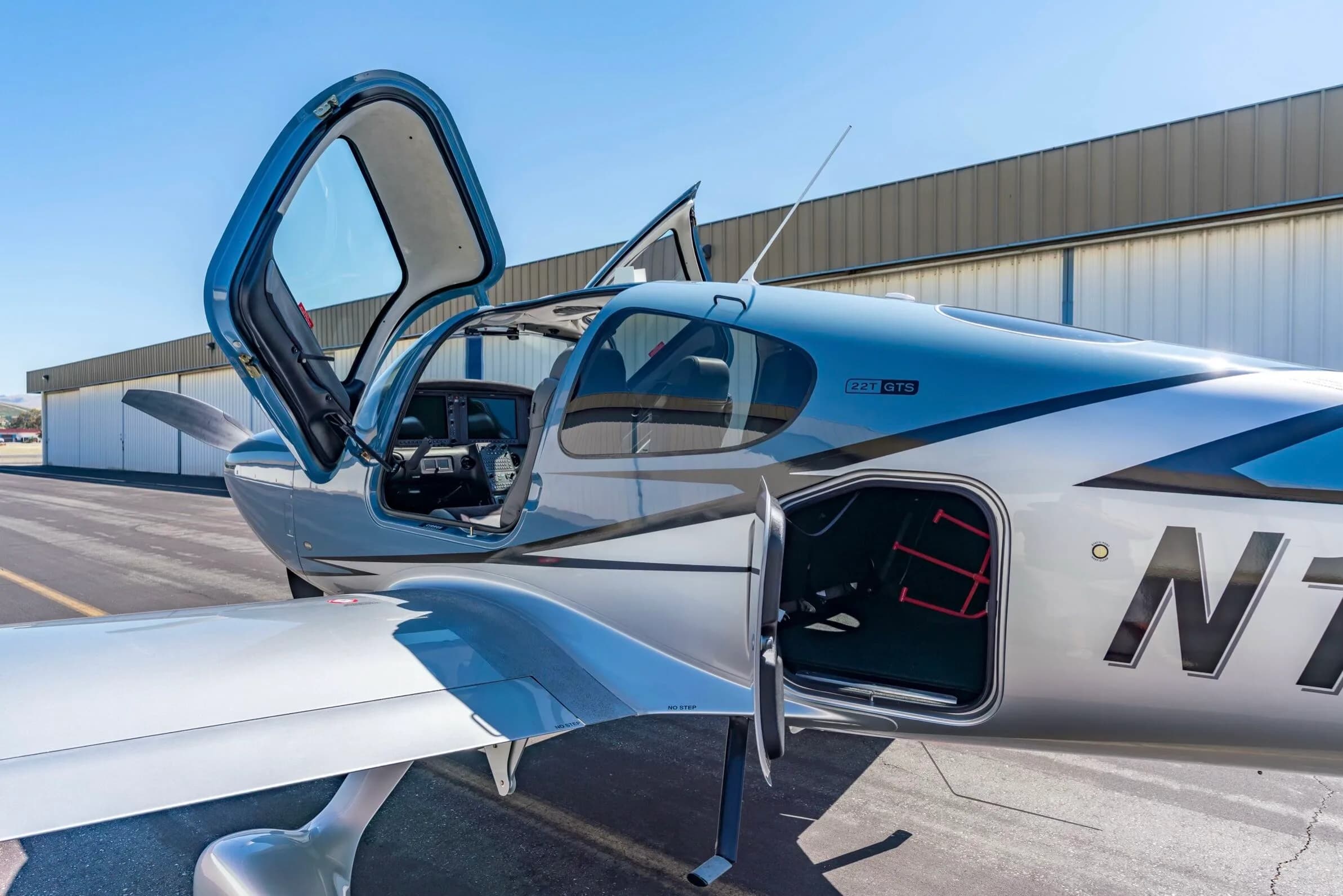 Close-up view of the open door and baggage compartment of a light blue and silver Cirrus SR22T aircraft, N1383Z.