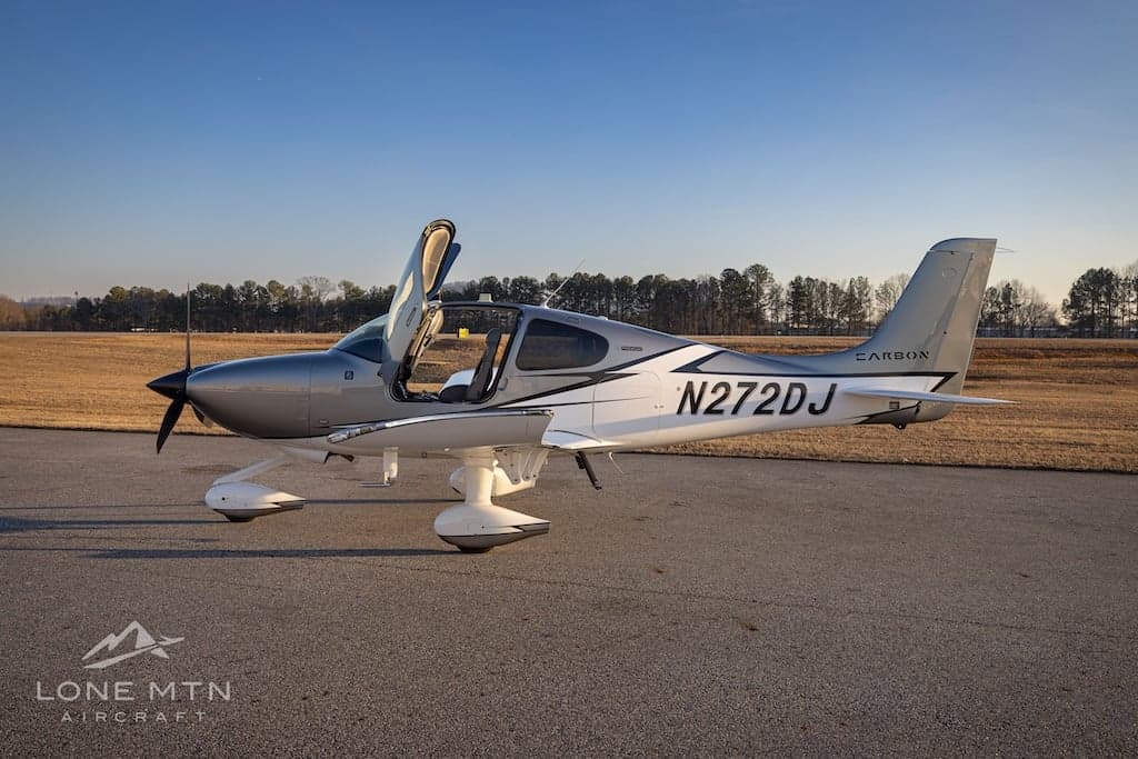 A Cirrus SR22T aircraft with open doors is parked on the tarmac.