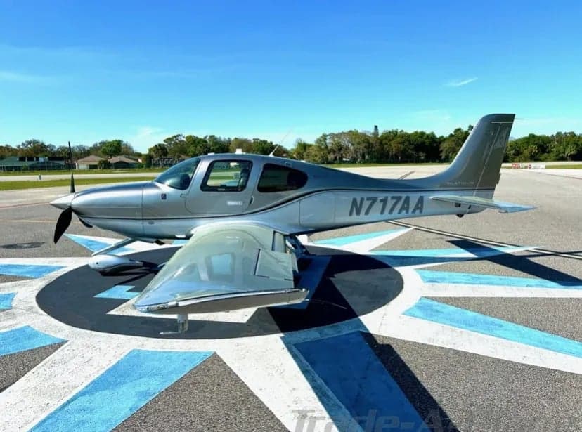 A side view of the silver Cirrus aircraft N717AA on a ramp.
