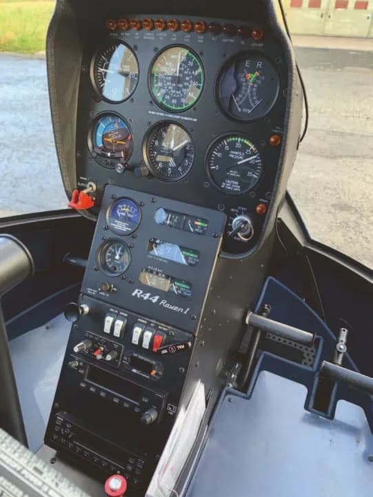 The detailed instrument panel and controls of a Robinson R44 Raven I helicopter cockpit.
