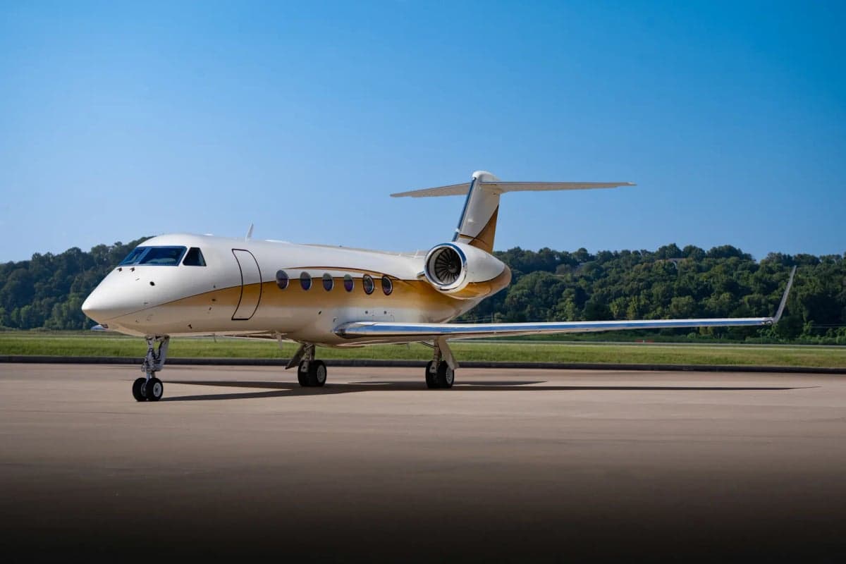 Gulfstream G450 aircraft parked on the tarmac with a white and gold paint scheme.
