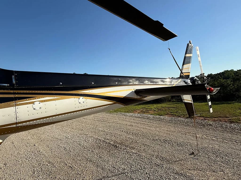 A close-up view of the black, white, and gold tail boom and horizontal stabilizer of the helicopter.