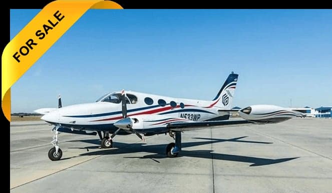 A white and red turboprop aircraft is parked on the tarmac with a 'FOR SALE' banner.