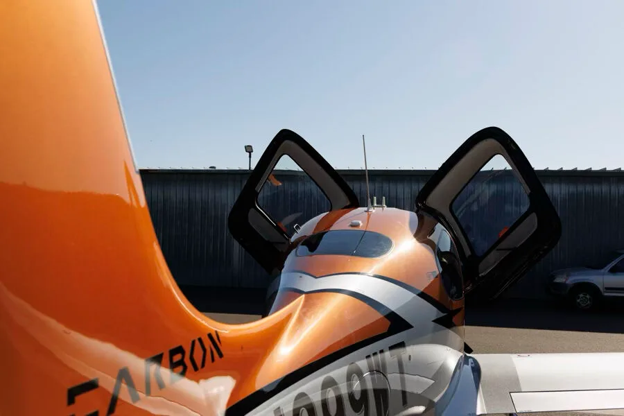 Close-up rear view of the orange tail and open doors of a Cirrus SR22T GTS aircraft with registration N299WT.