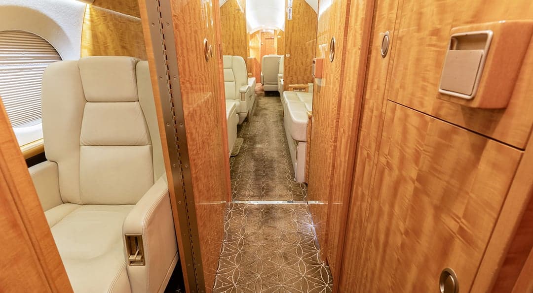 The aircraft's interior features cream-colored leather seats and wood paneling.