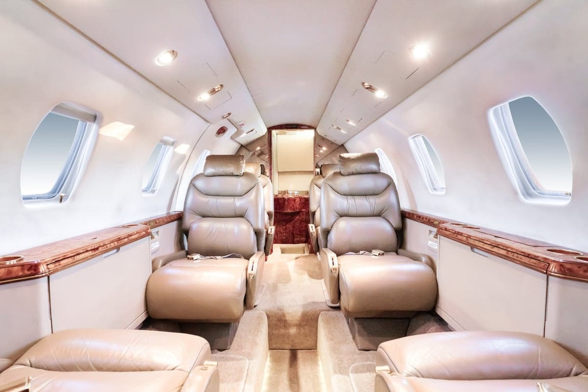 The interior of the aircraft features leather seats and wood trim.