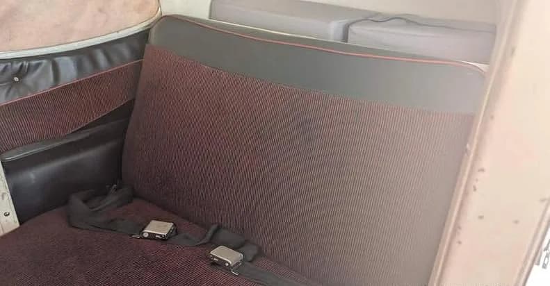 A close-up view of the rear cabin seats of the Cessna 172M, upholstered in maroon striped fabric with black trim.