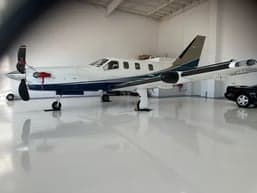 A TBM 930 aircraft is parked inside a hangar, showcasing its white and blue paint scheme.
