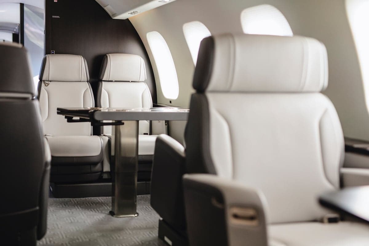 Close-up view of the aircraft interior with white leather seats and a table.