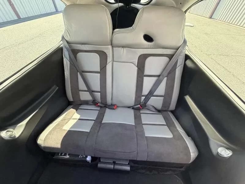 The two-tone gray rear passenger seats with seatbelts inside the aircraft cabin.