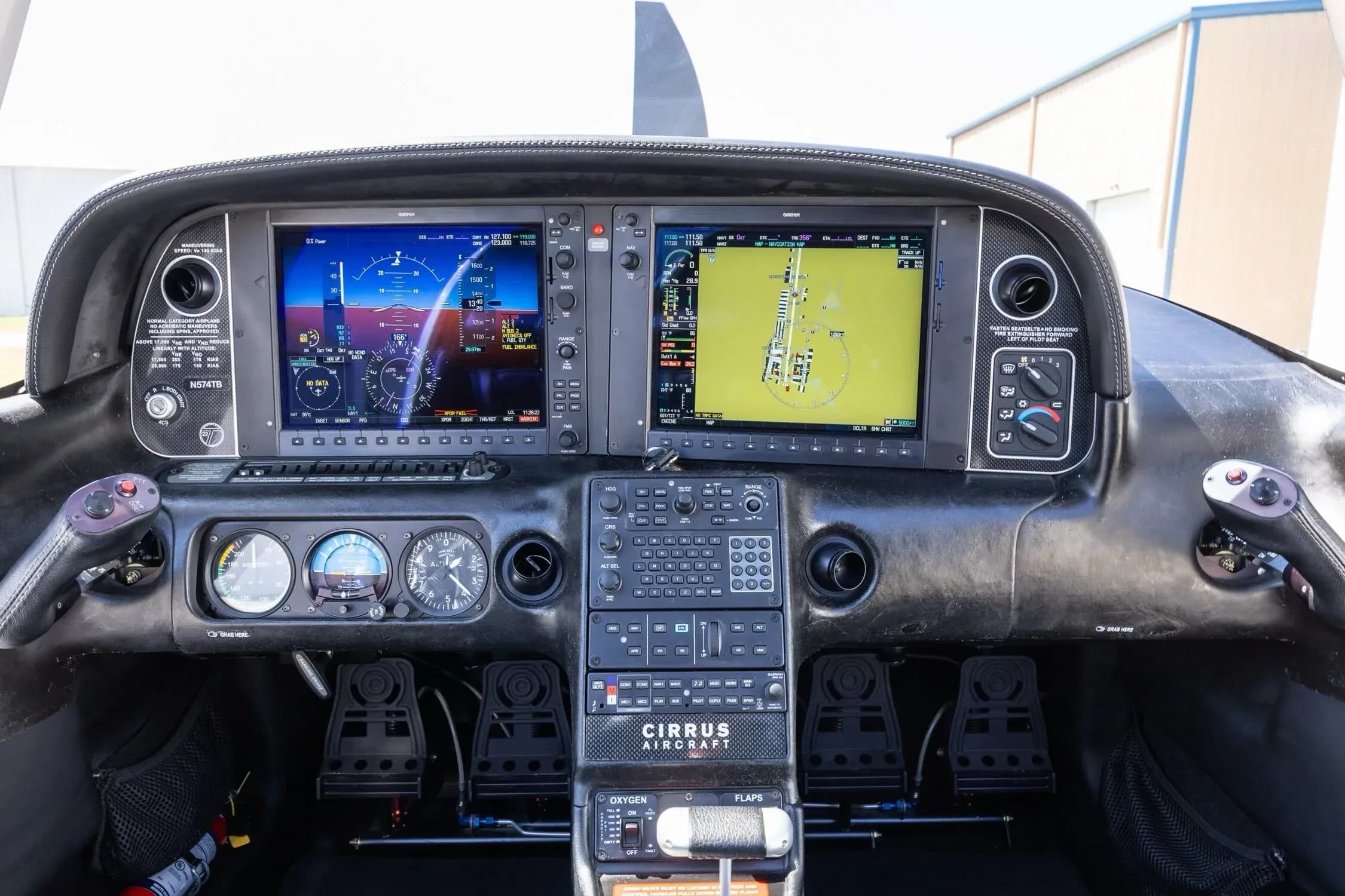 A detailed view of the Cirrus SR22 cockpit instrument panel, displaying two large digital screens and various controls.