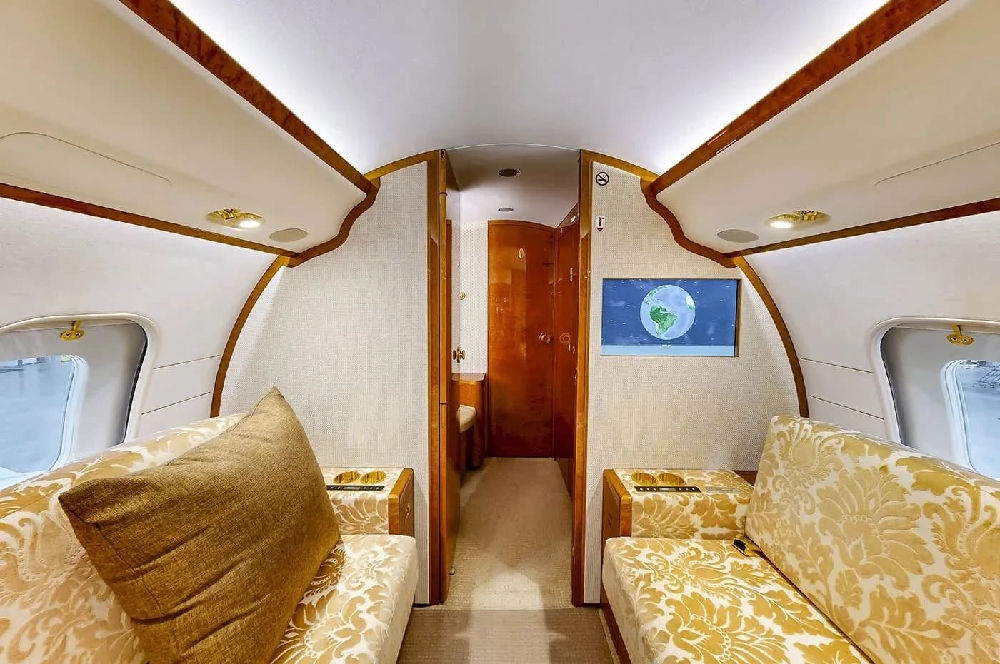 A section of the aircraft cabin featuring two patterned fabric couches facing each other, with a screen displaying a globe.