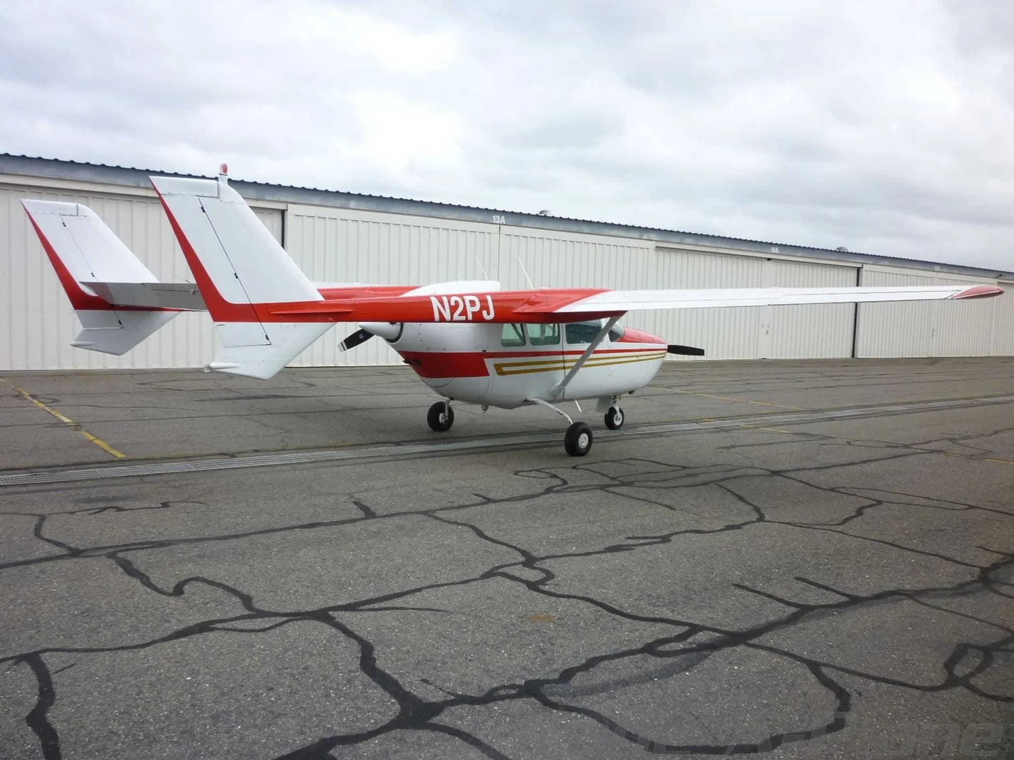 A rear-side view of the white and red Cessna Skymaster N2PJ parked on an asphalt apron.