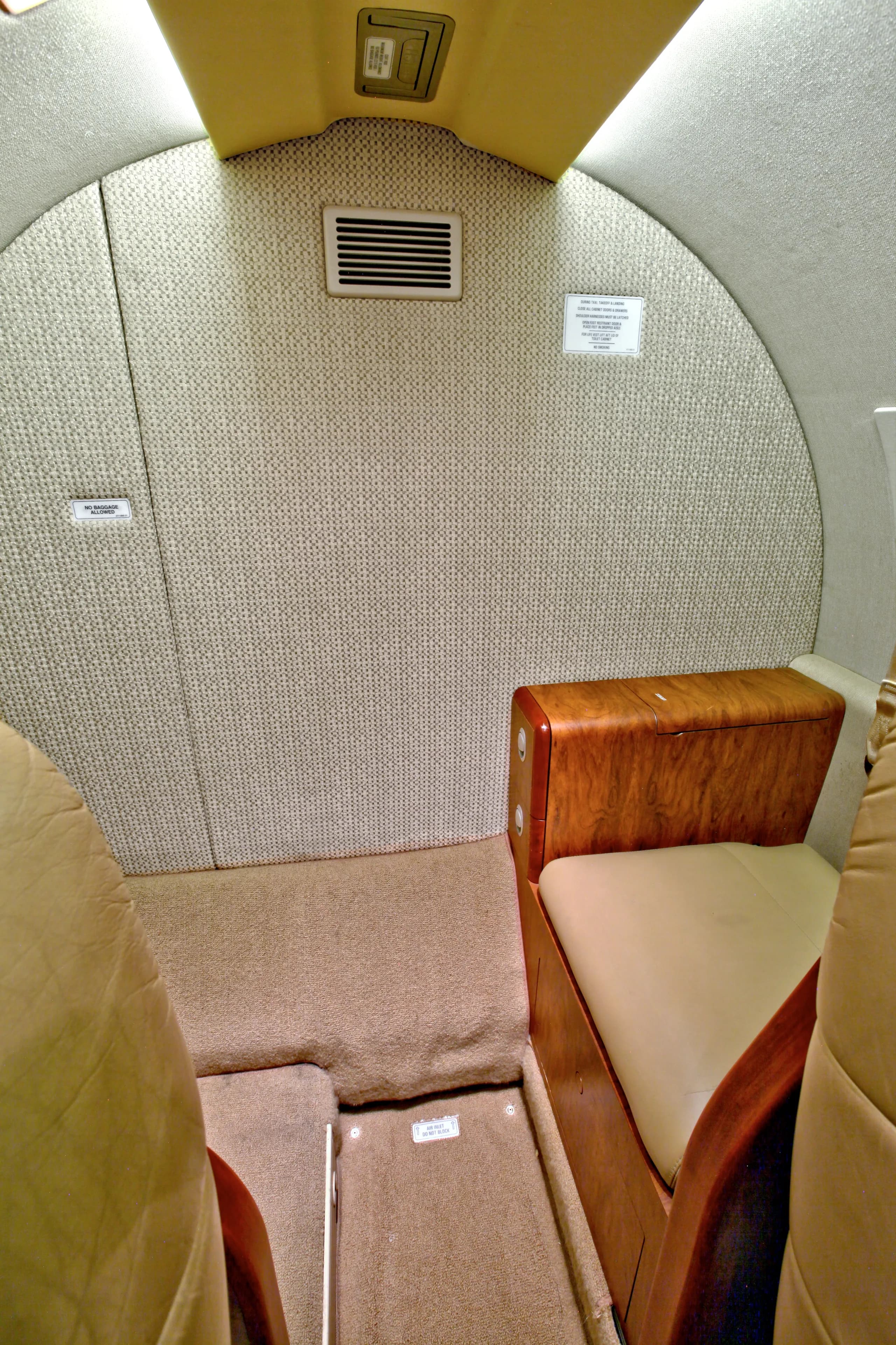 The rear interior of a Cessna Citation CJ1+ featuring a seat and carpeted wall.