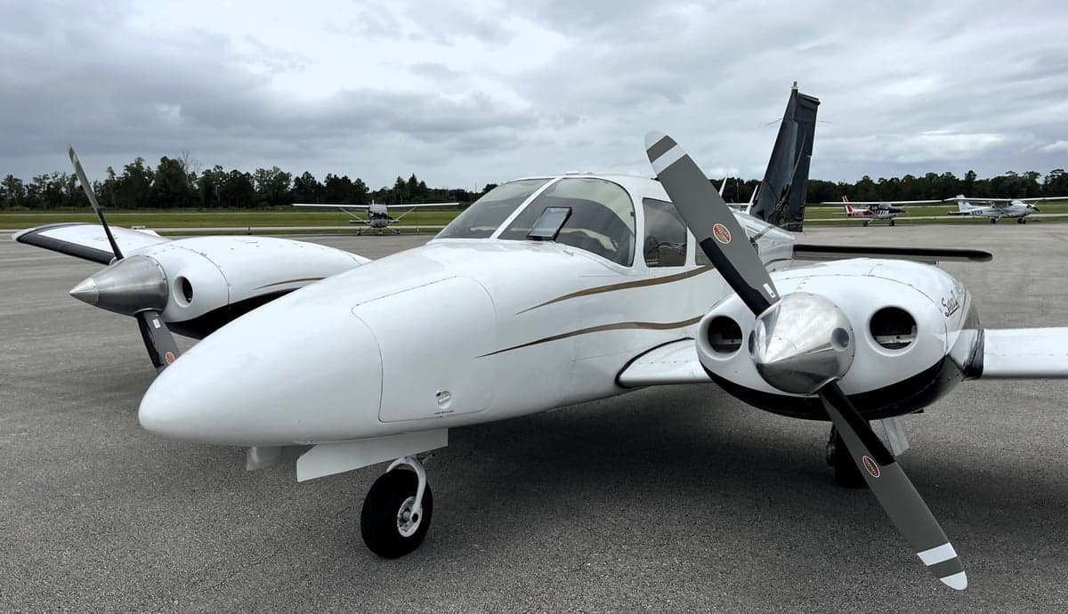 Close up of the front of a Piper Seneca II aircraft with a white and black paint scheme.