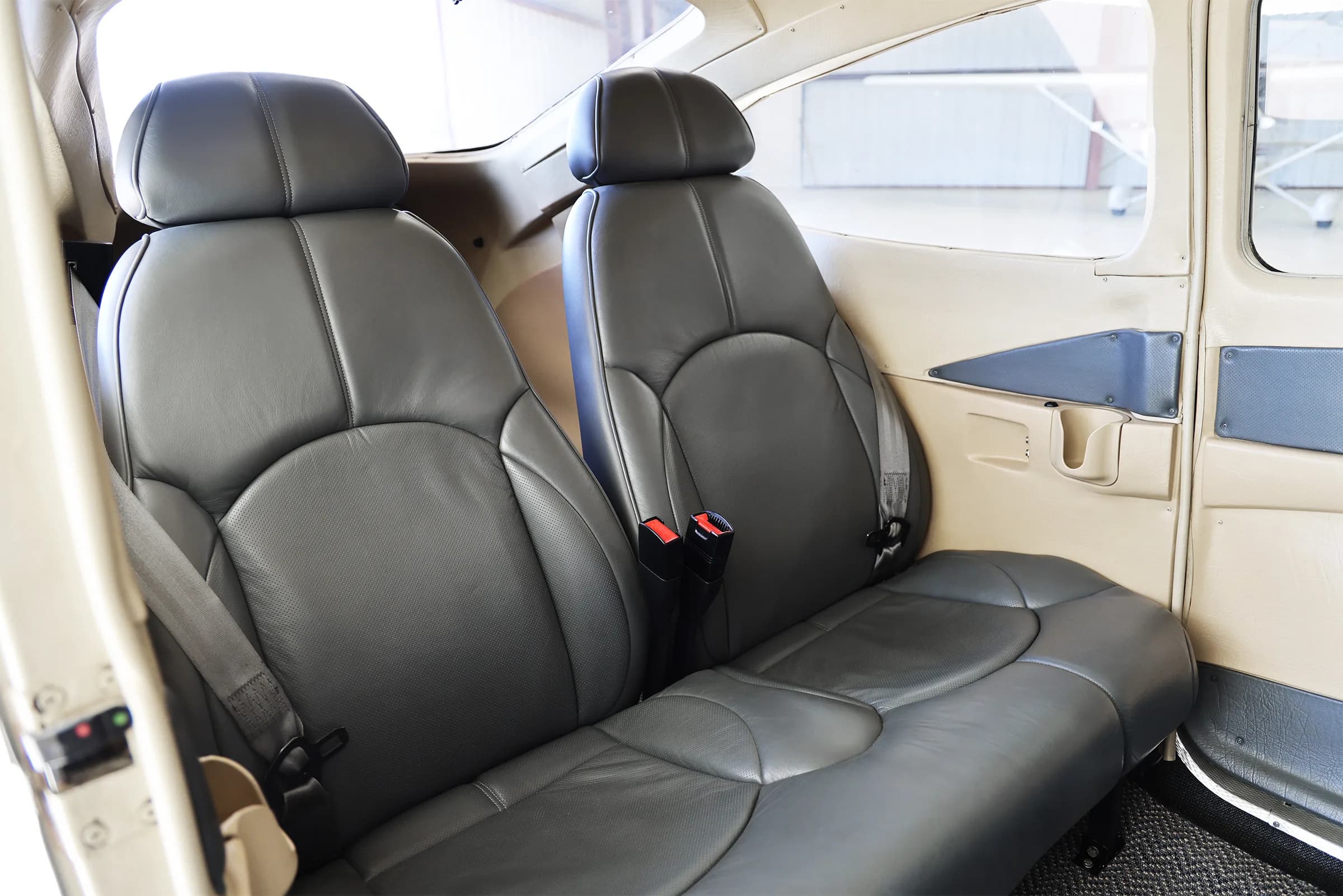 The grey leather front and rear seats of a Cessna 182 Skylane interior.
