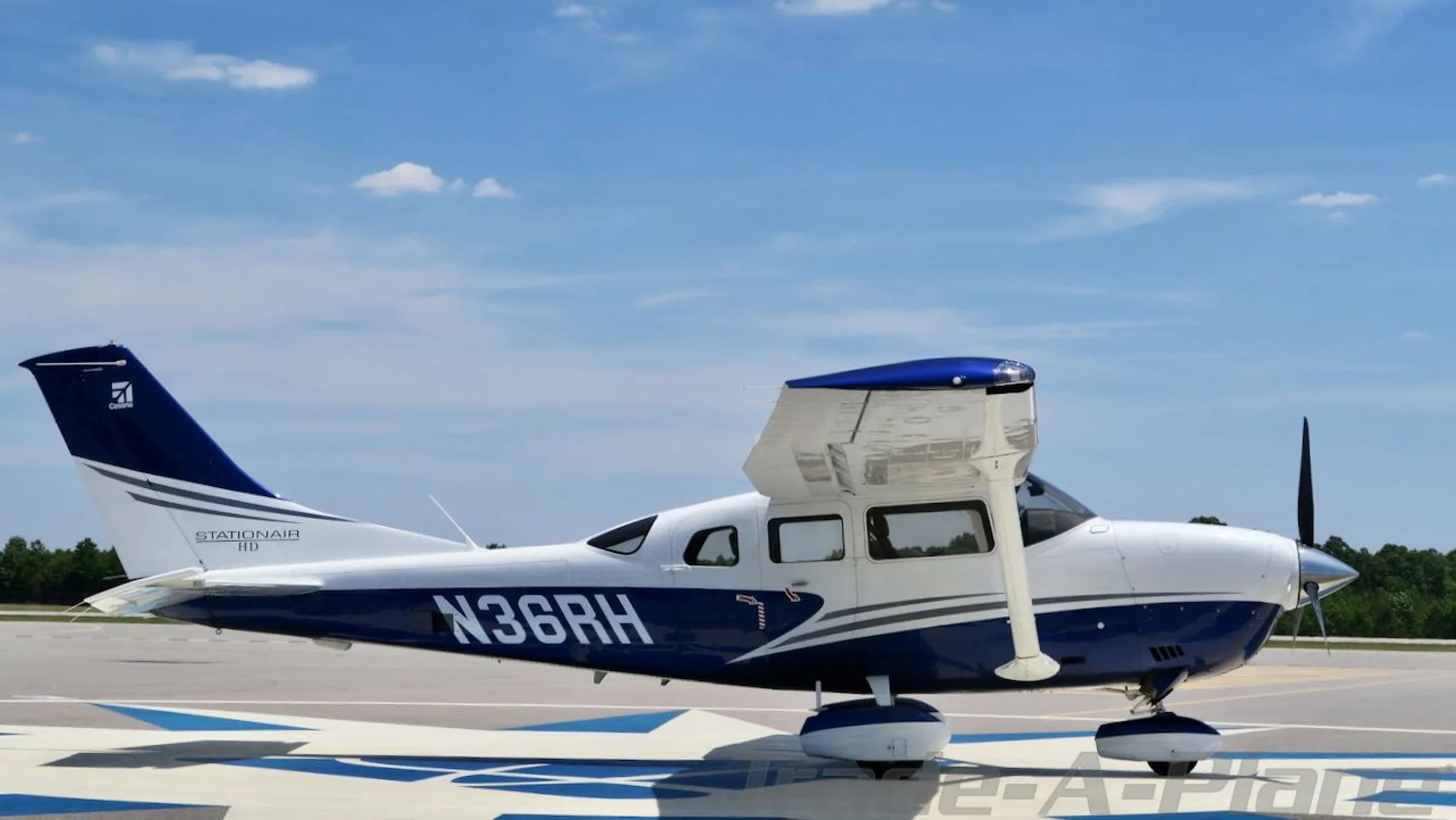 Side view of a white and blue Cessna Stationair HD (N36RH) on an airfield.
