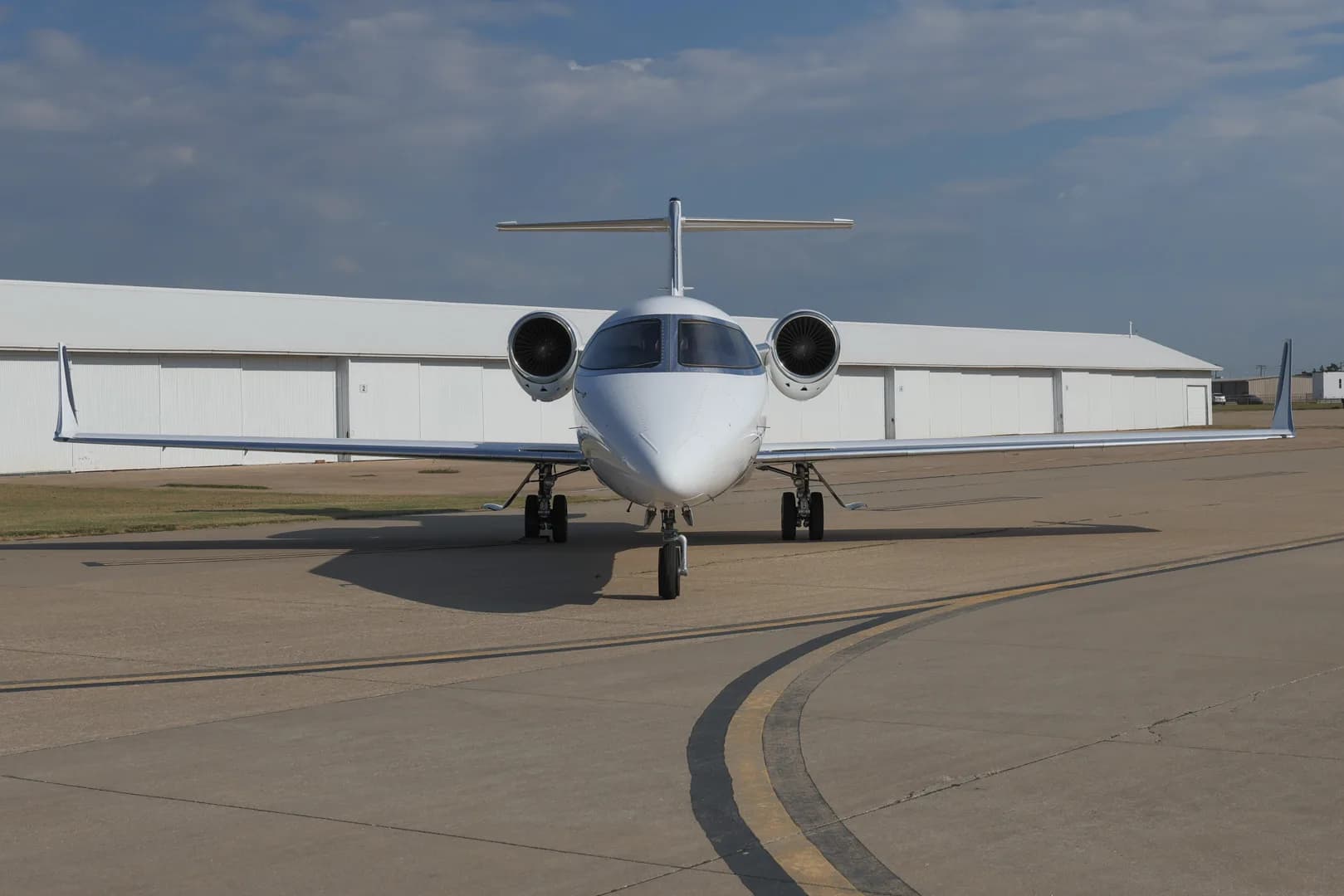 Front view of the white jet N711BH on the tarmac.