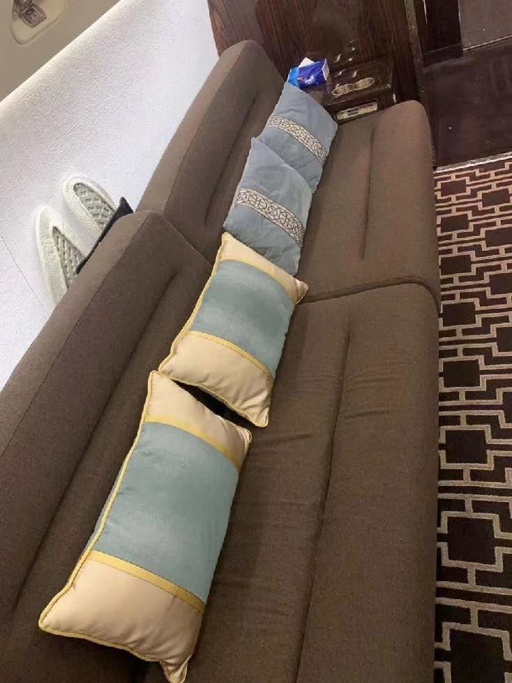 Close-up of a brown sofa with blue and cream pillows inside the aircraft cabin.