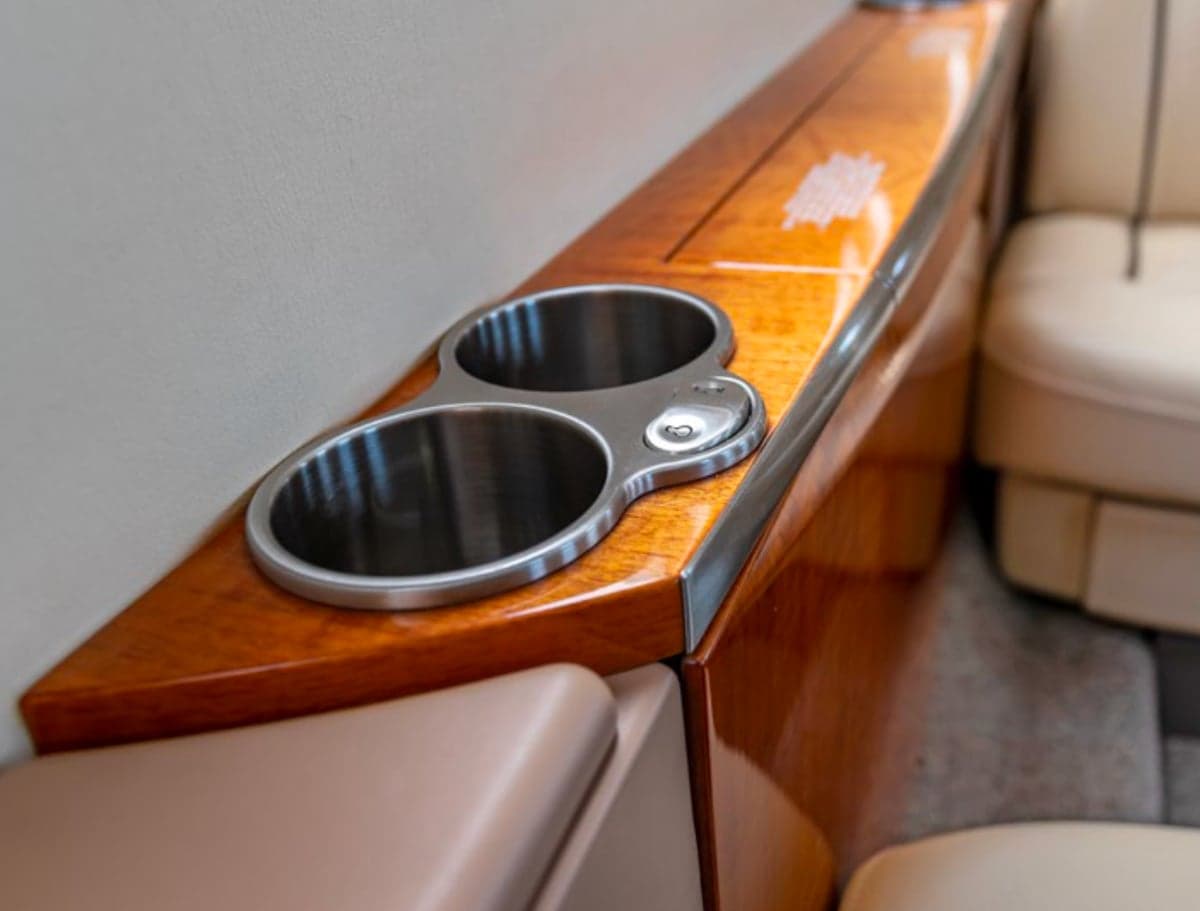 Close-up of a wooden side table with cup holders in the aircraft interior.
