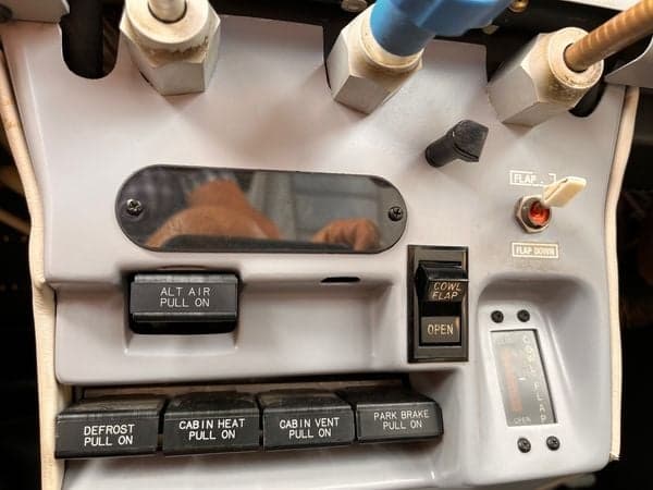 Close-up of the aircraft's cockpit controls, including the flap switch and cowl flap control.