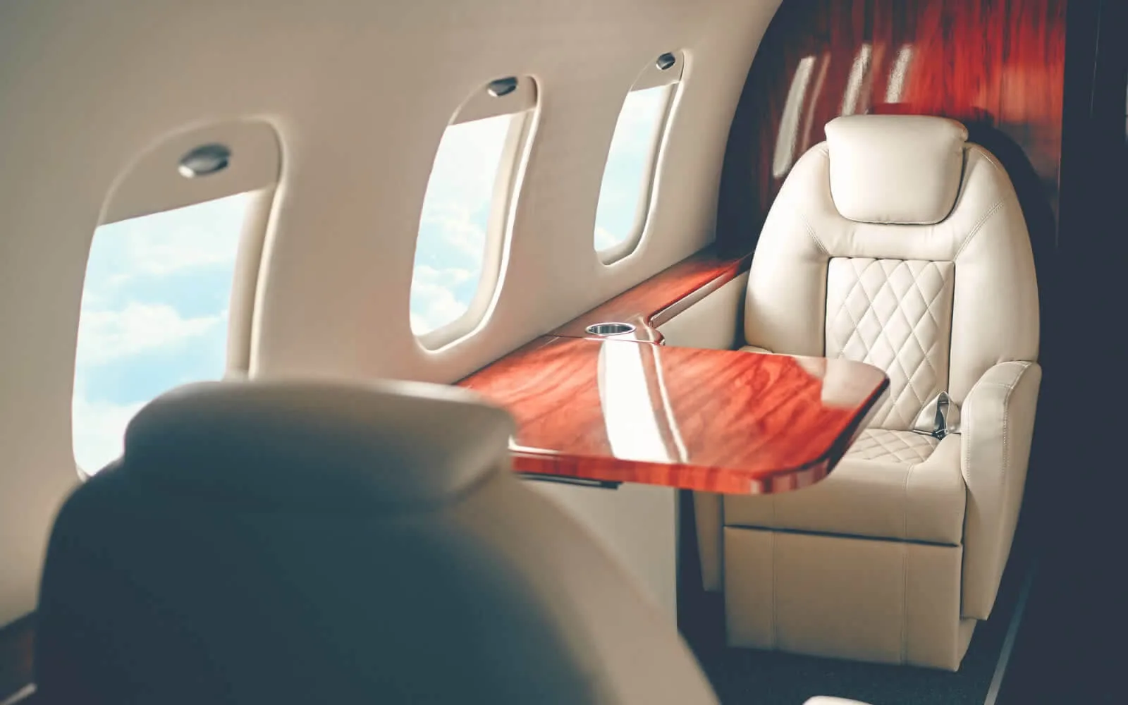 A luxurious leather seat and wood table inside an aircraft cabin.