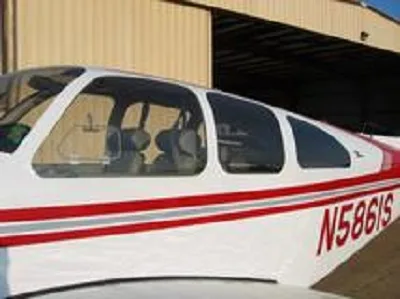 Close-up view of the white and red fuselage and cabin windows of a Beechcraft Bonanza N5861S.