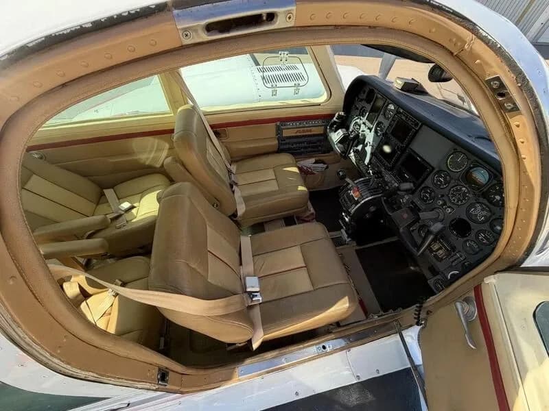 View into the cabin of a Cessna 310 aircraft showing tan leather seats and the cockpit instrument panel.
