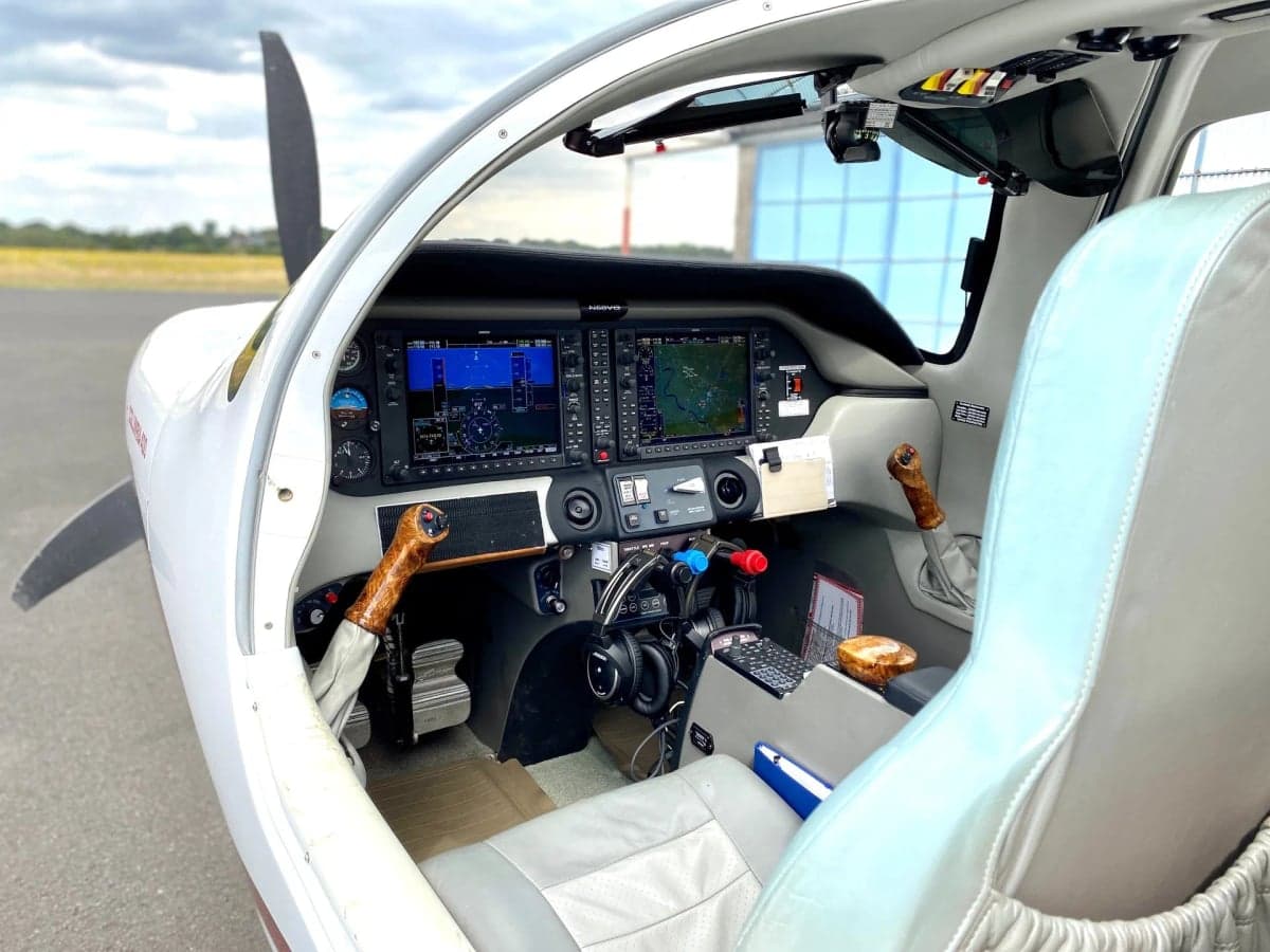 View of the cockpit of the Columbia 400 aircraft with dual screens and wooden control sticks.