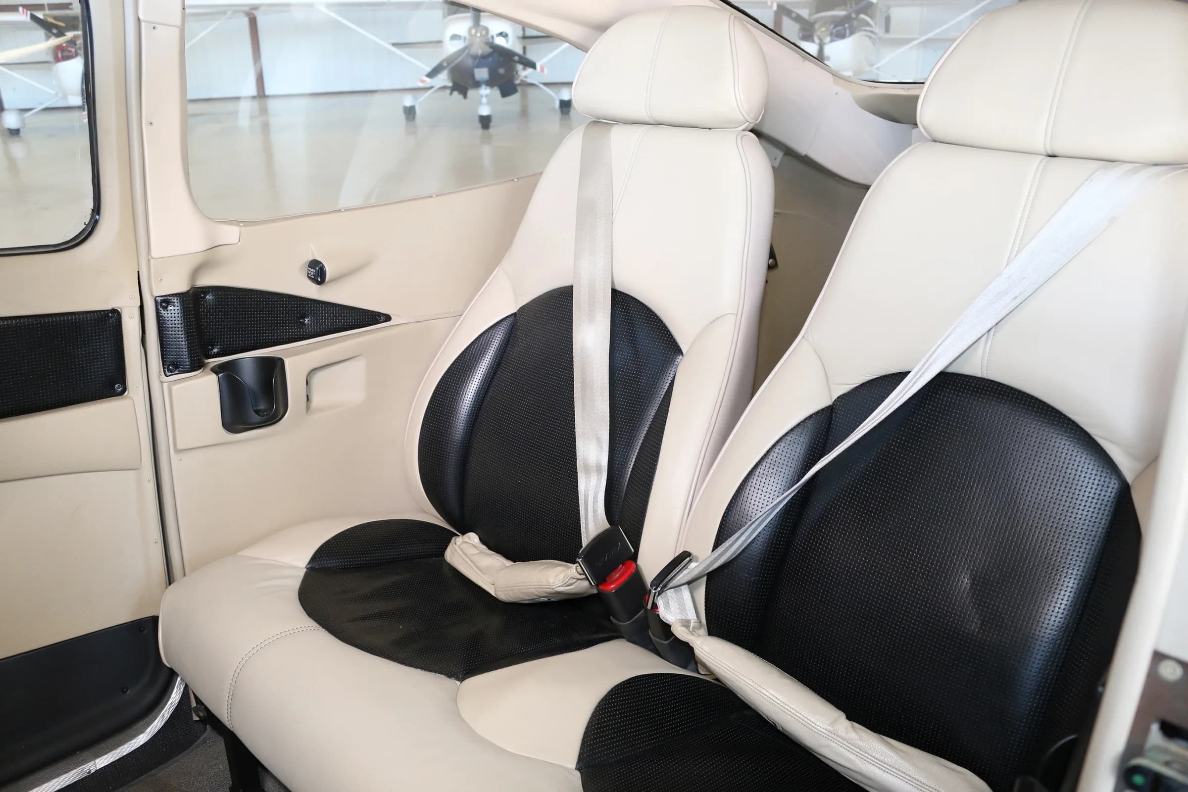 The cream and black passenger seats of a Cessna Skylane aircraft cabin.