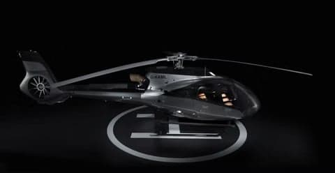 A dark helicopter parked on a helipad.